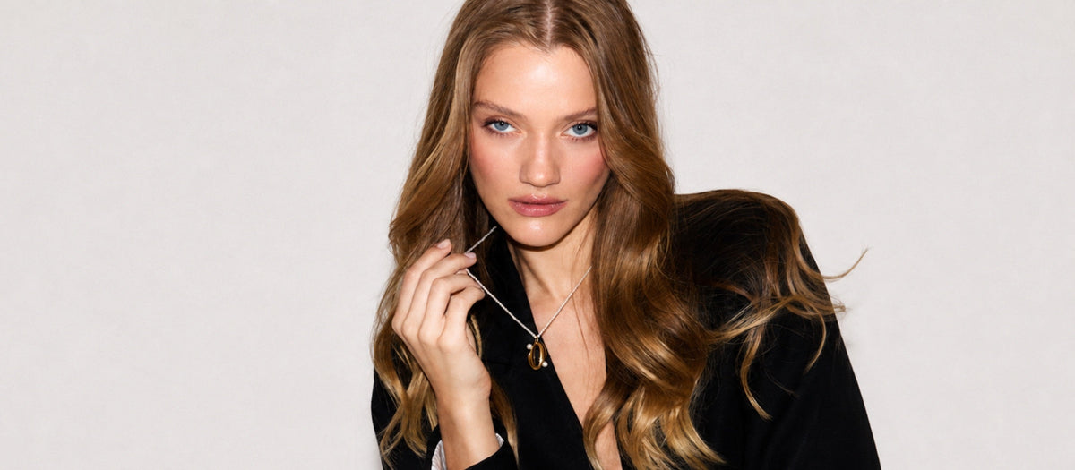 Woman wearing the Audrey Pointe Pendant from the Audrey Collection with freshwater cultured pearls and 18K gold-plated sterling silver on a black blazer.