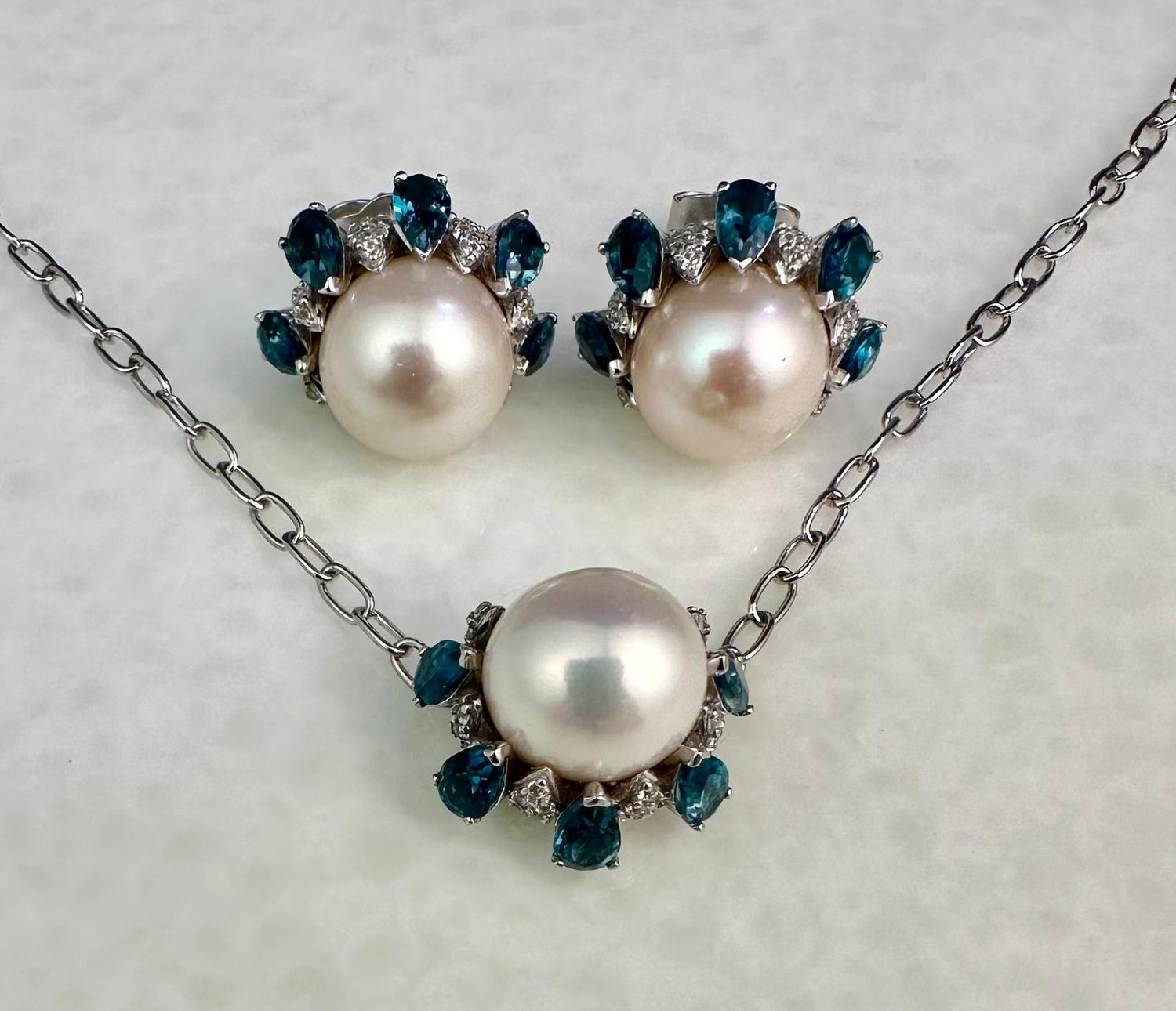 Pearl necklace and earrings with London blue Topaz on a light gray background
