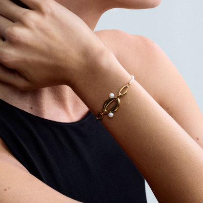 Editorial portrait of a model wearing the Audrey Swan Bracelet in 18K gold-plated sterling silver featuring white freshwater cultured pearls.