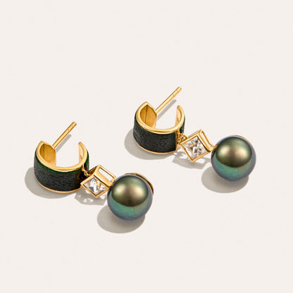 Angled view of the Luna Eclipse Earrings, showcasing green-black freshwater cultured pearls, natural white zircon and green leather in 18K gold-plated sterling silver.